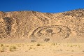 Le tumulus est constitué d'un grand amas de pierres, installées de façon circulaire, en forme dite de "trou à serrure" recouvrant la sépulture d'une personne de haut rang. Ce tumulus daterait de plusieurs milliers d'années. Son orientation à l'est suggère la pratique d'une religion liée au soleil. tumulus,sahara,algerie. 